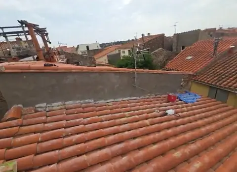Après : toit contre mur en pierre, tuiles reprises par ASJ Toiture